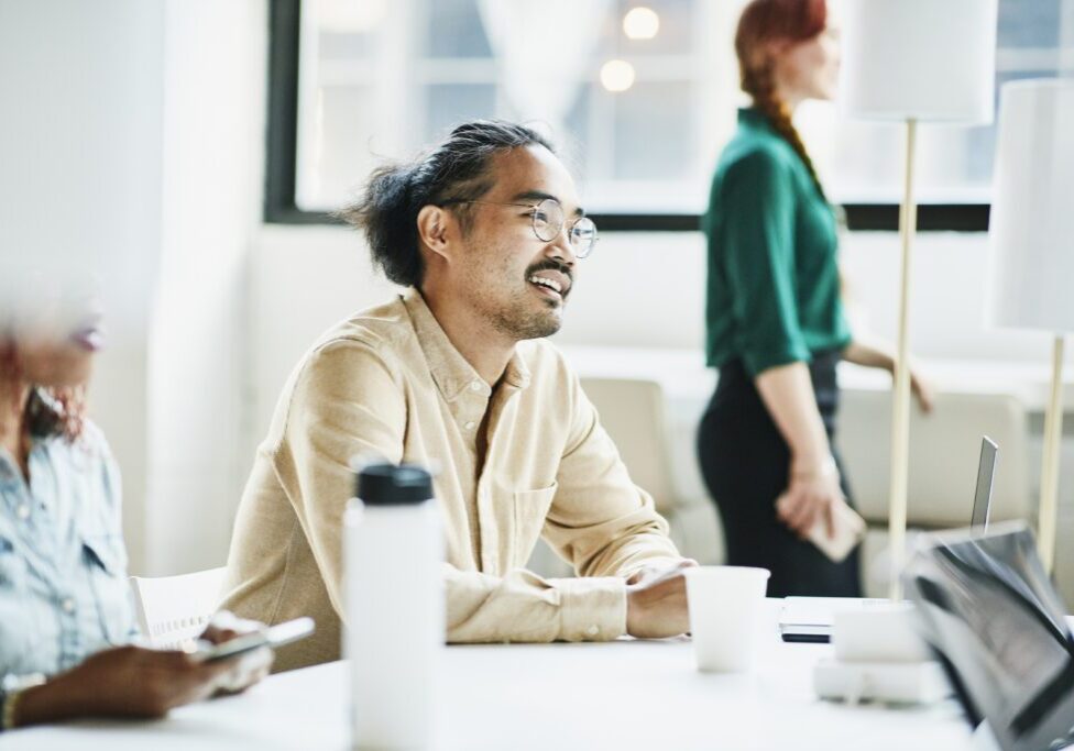 Smiling businessman in discussion with colleagues while working on project in office