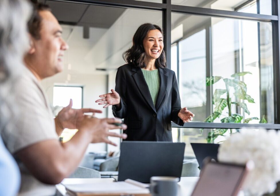 Young businesswoman speaking to colleagues in modern conference room