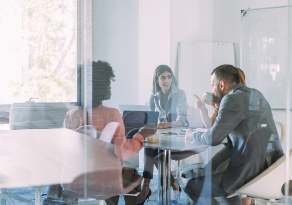 Group of business persons in business meeting. Group of entrepreneurs on meeting in board room. Creative business team on meeting in the office. The view is through glass.