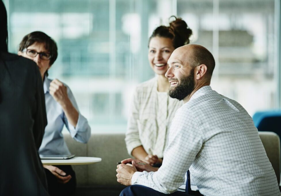 Smiling businessman in discussion with colleagues during informal project meeting in office